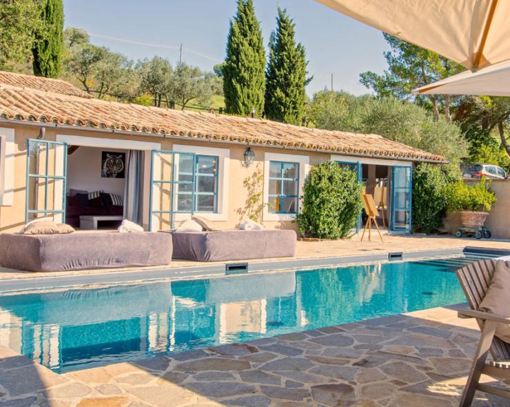 Sunny pool, rustic villa, summer relaxation amidst cypress trees and blue sky.