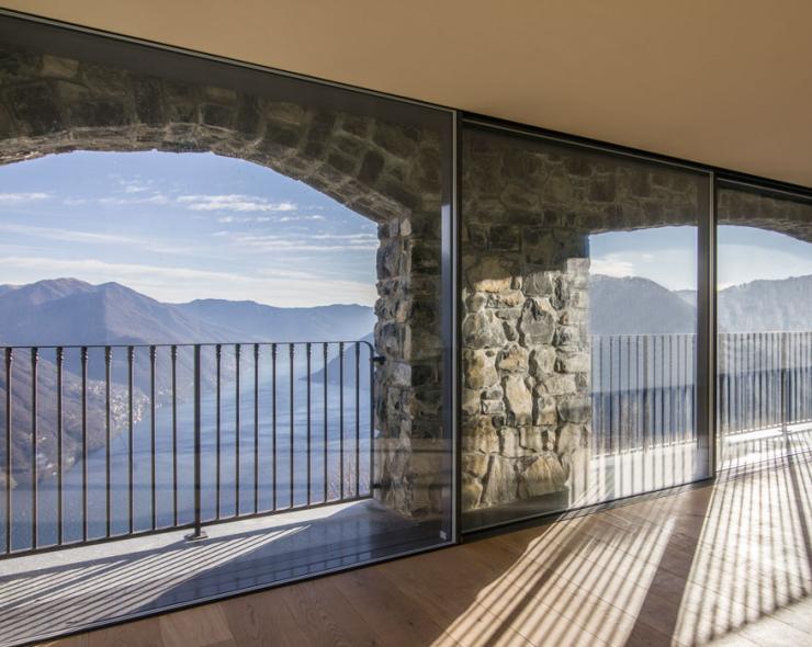 Breathtaking view of mountains and lake through stone arches and bright glass.
