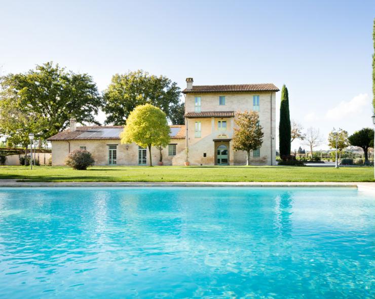 Rustikale Villa mit Pool, üppigen Bäumen und klarem Himmel: eine Oase der Ruhe.