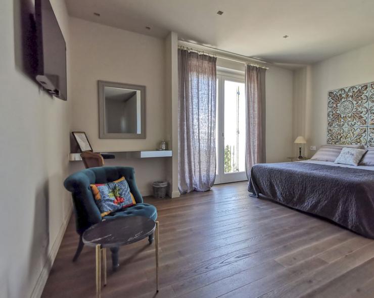 Elegantes Zimmer mit Doppelbett, gemütlichem Sessel und natürlichem Licht.